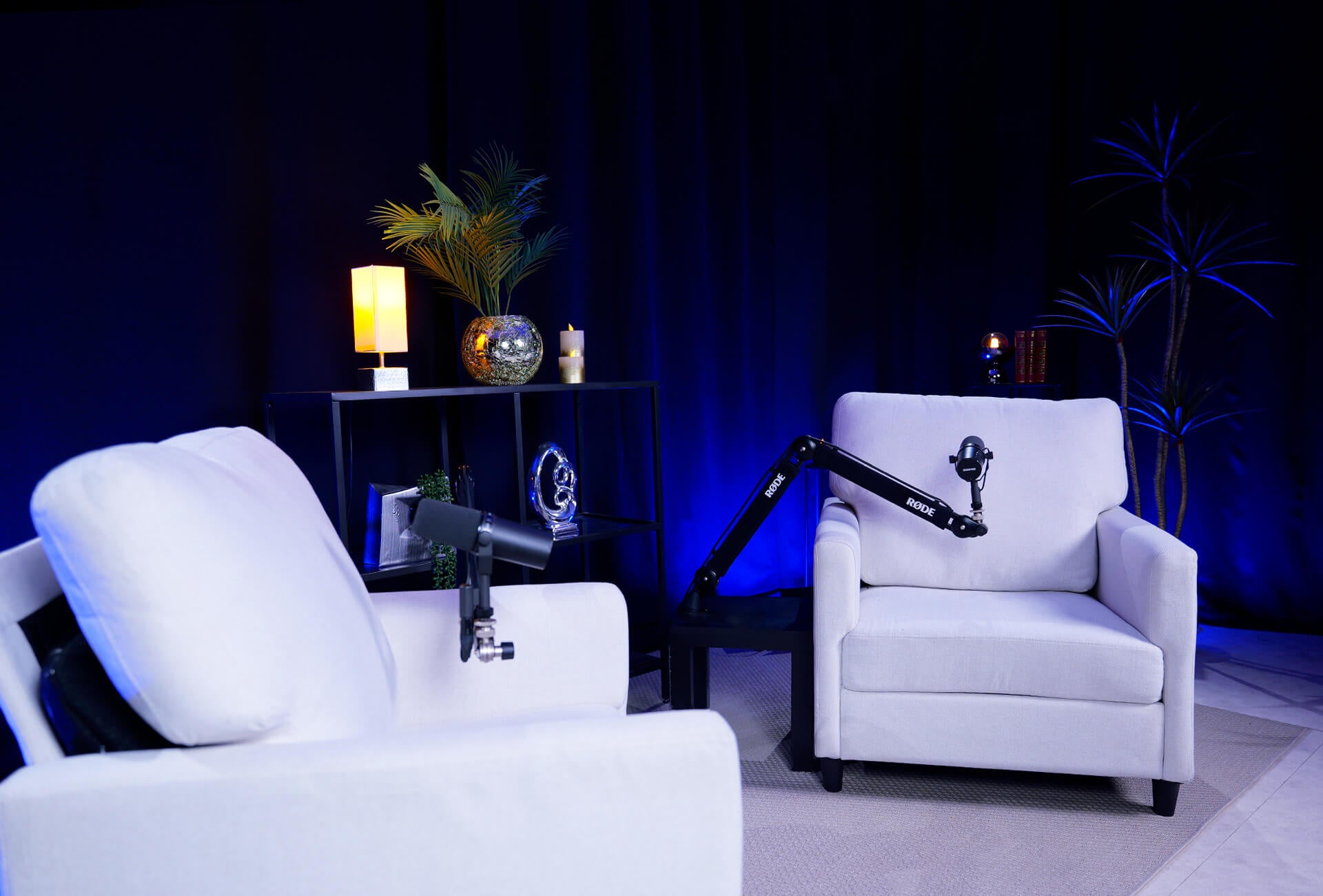 Décor de podcast avec un fond noir et des fauteuils blancs en premier plan