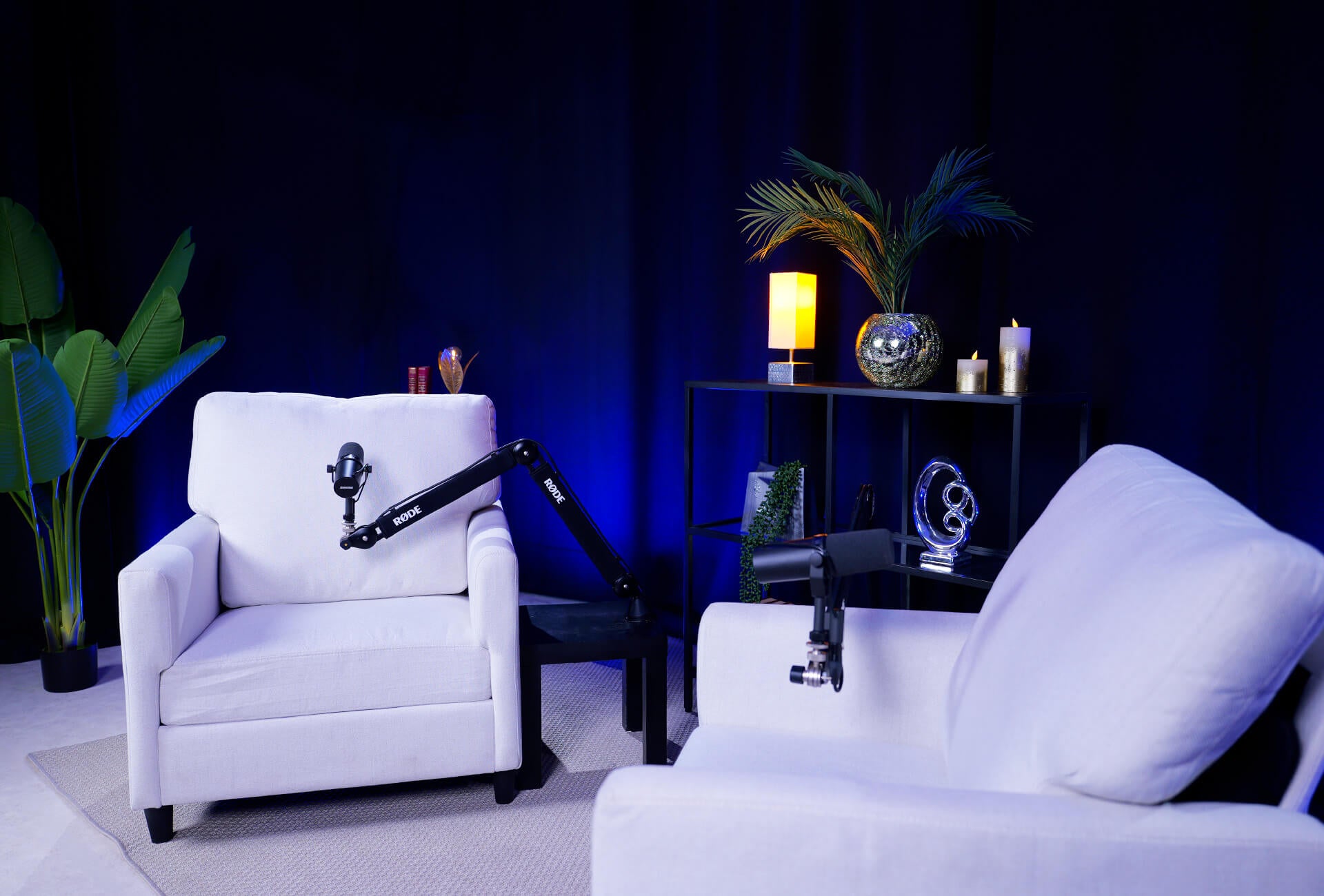 Fauteuils blancs sur un décor de podcast noir avec des jeux de lumières bleu