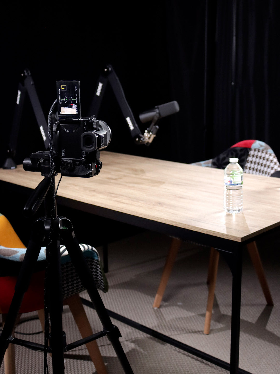 Caméra en premier plan avec une table et une chaise et un micro en arrière plan 