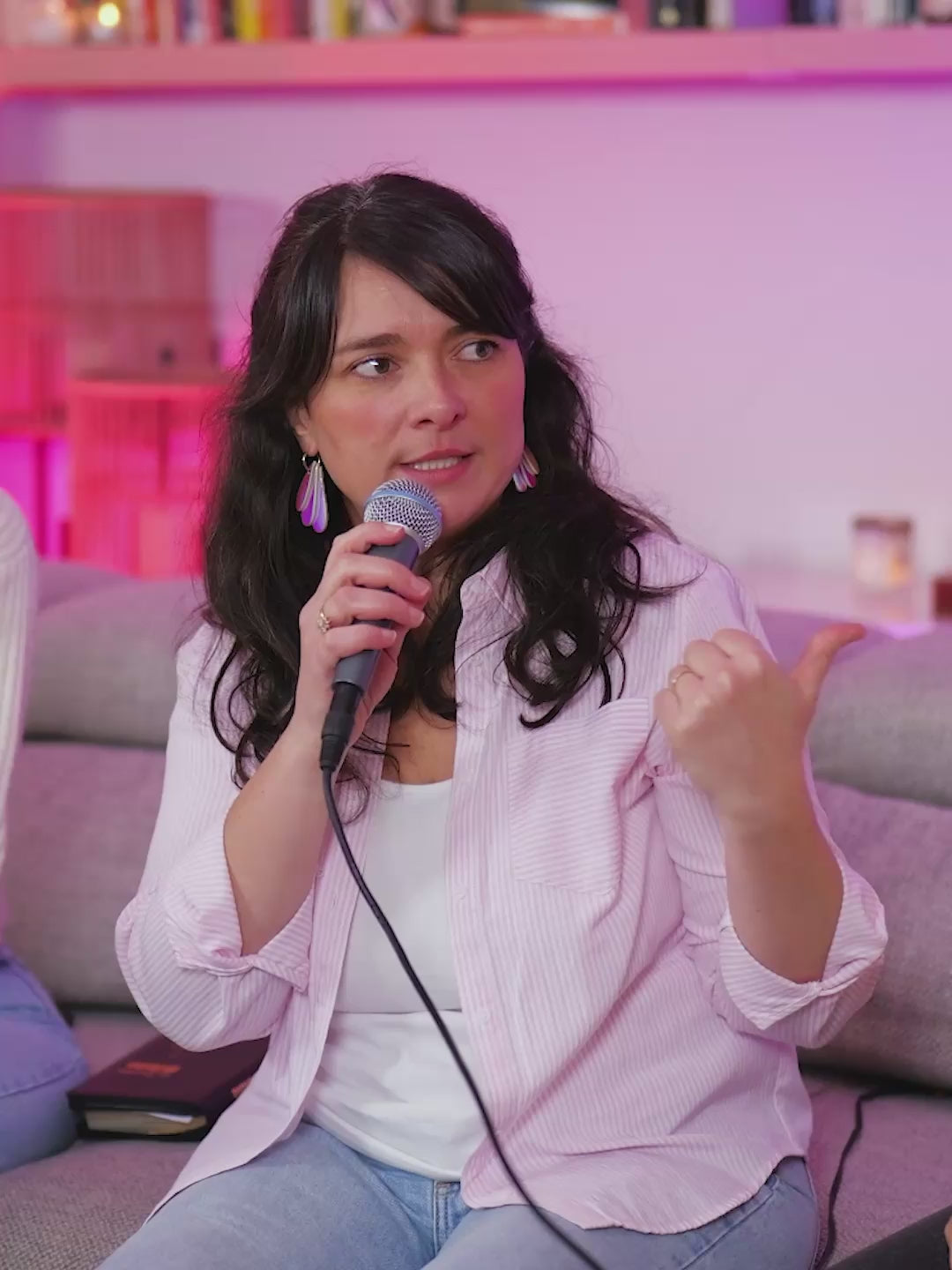 Charger la vidéo : Femme installée dans son canapé qui parle dans un micro, ambiance rose