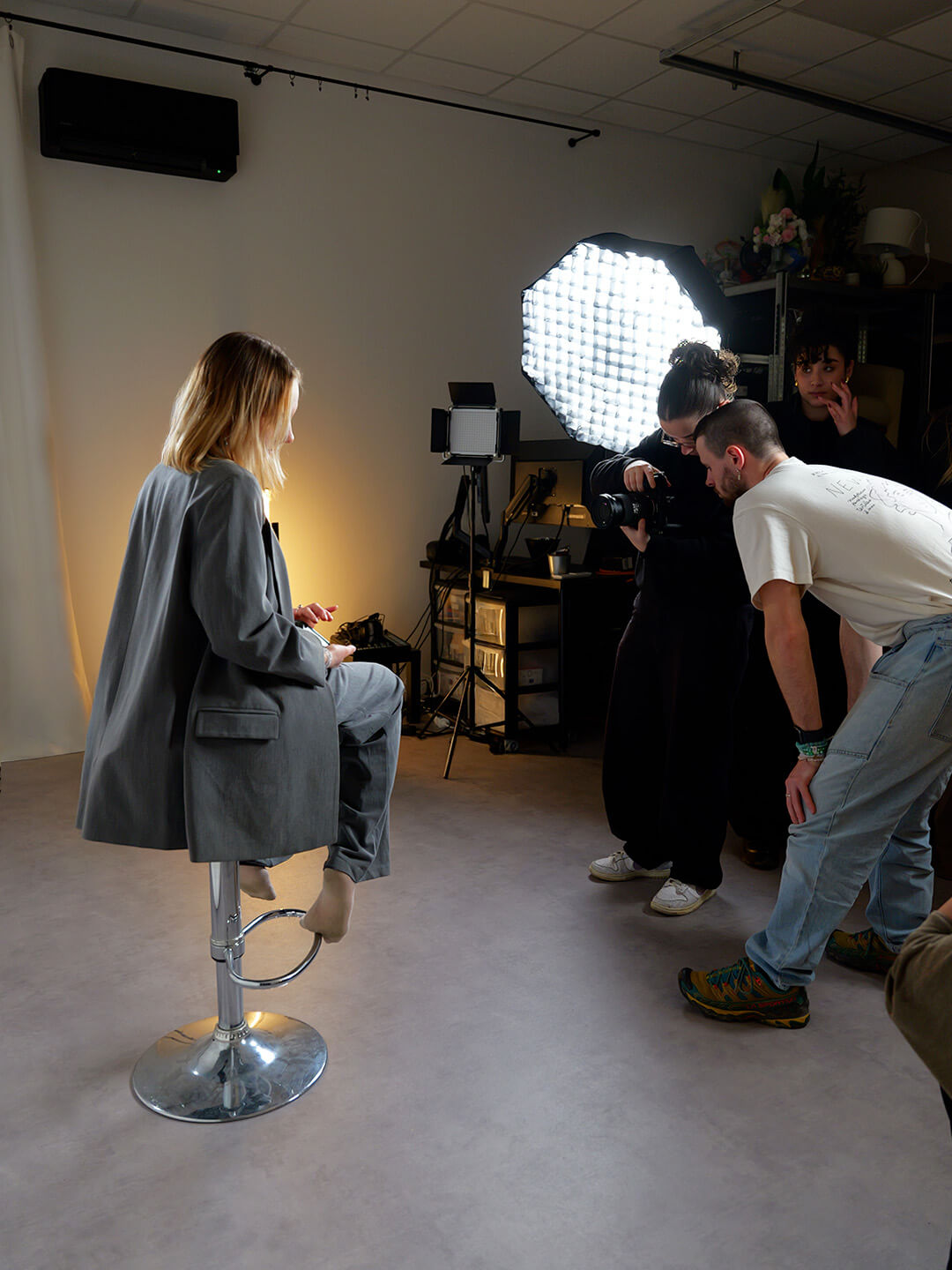 Equipe de production en train de shooter une fille assise sur un tabouret