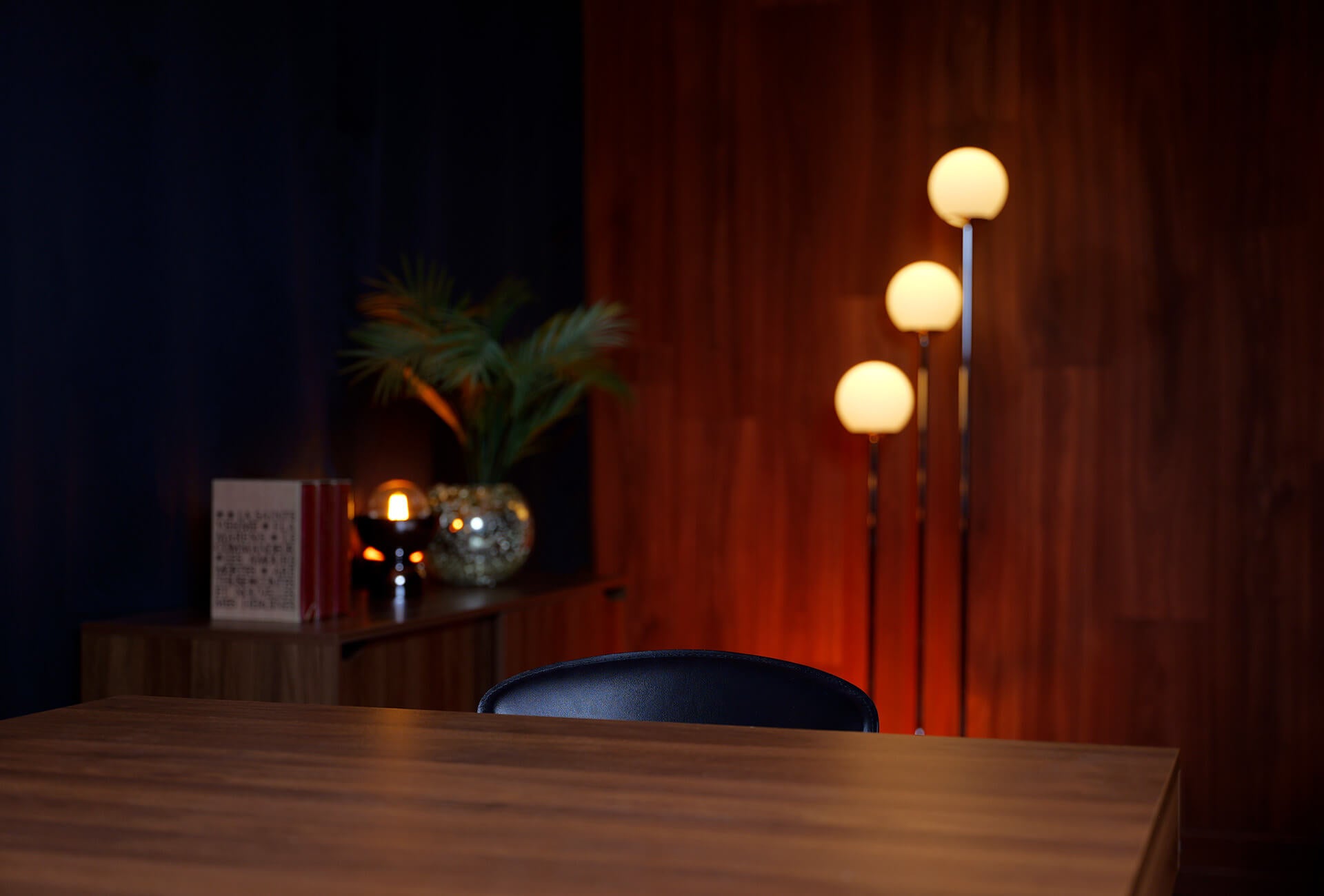Table en bois en premier plan avec un mur en bois éclairé en orange en arrière plan